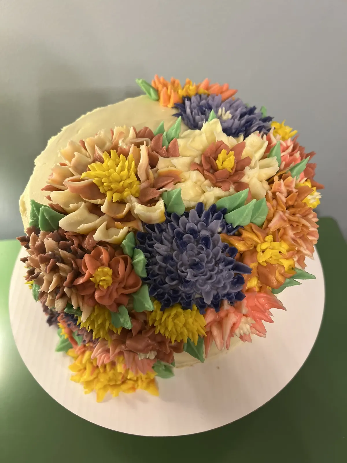 Cake topped with piped buttercream flowers in fall colors