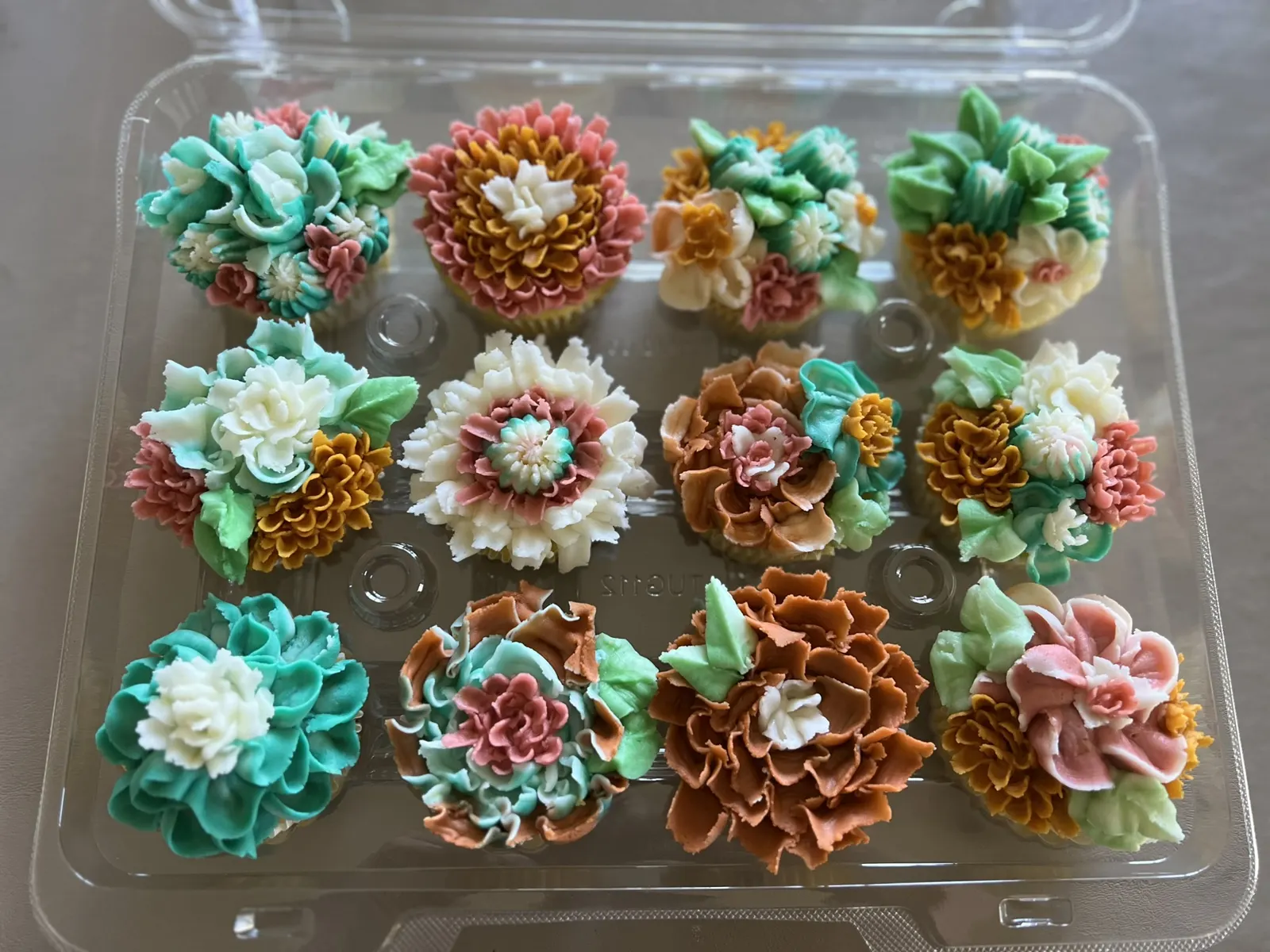 A dozen cupcakes piped with buttercream flowers