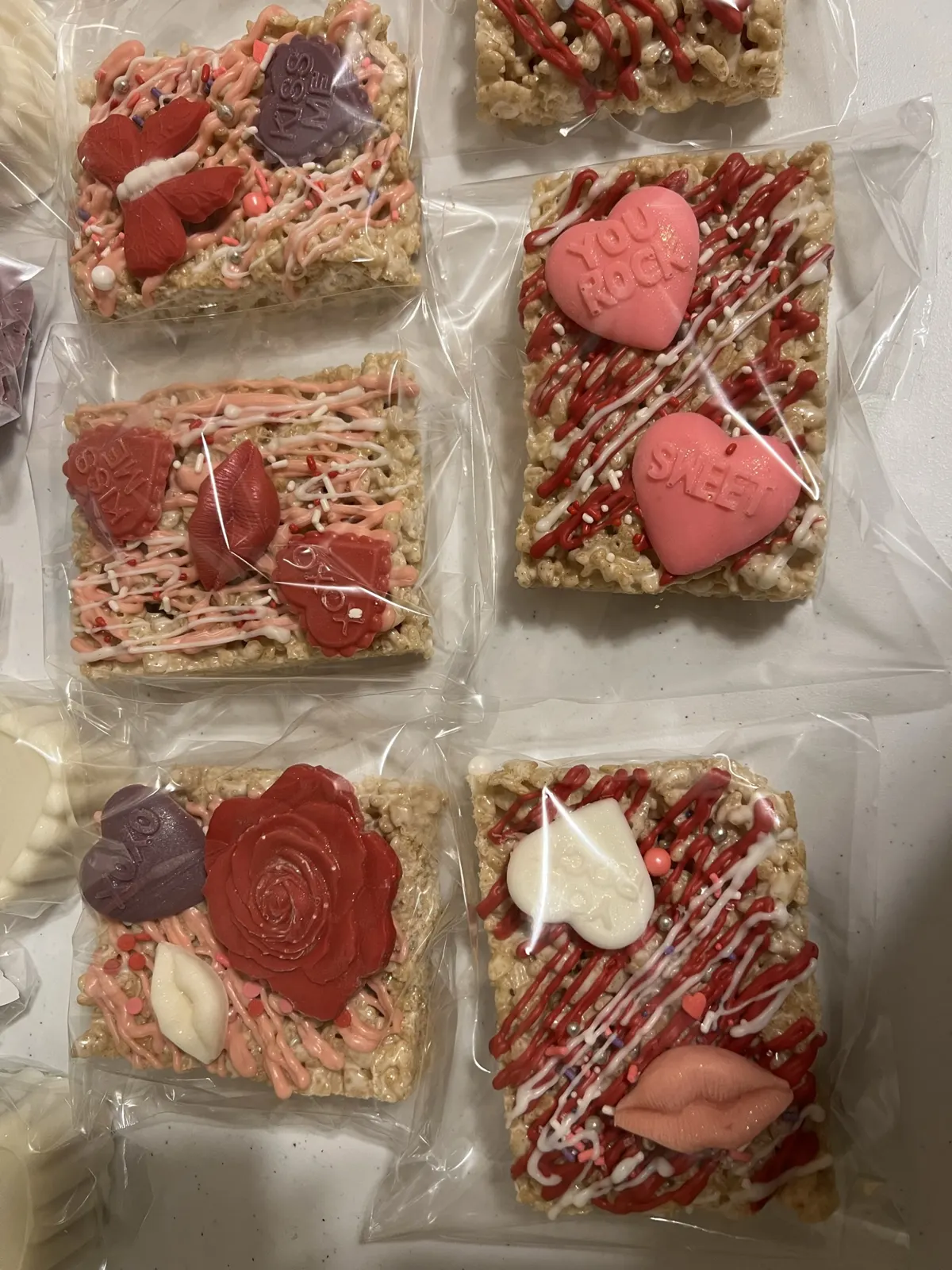 Rice Krispie treats topped with pink drizzle, hearts and candy lips